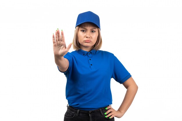 Una joven mensajero de vista frontal en uniforme azul posando y mostrando la señal de stop