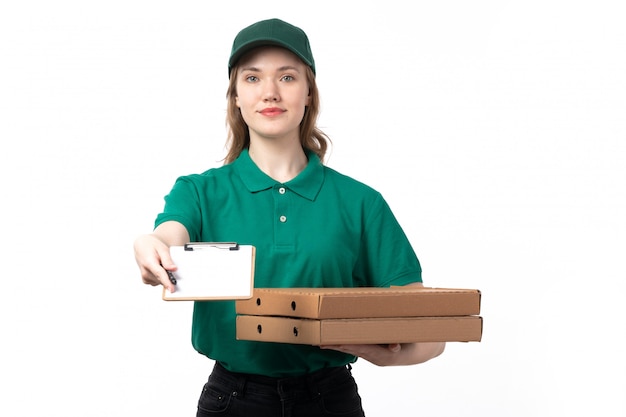 Una joven mensajero de vista frontal en uniforme verde sosteniendo cajas de pizza y bloc de notas