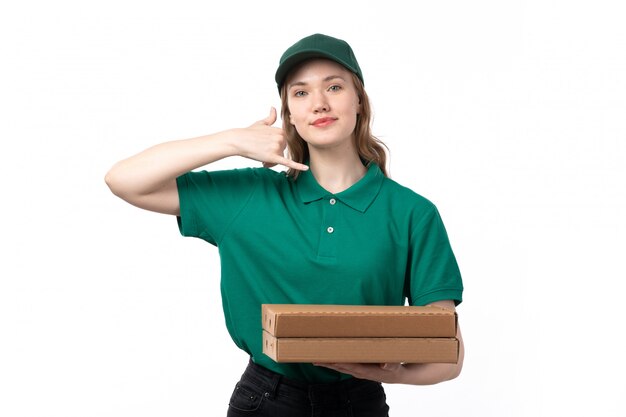 Una joven mensajero de vista frontal en uniforme verde sosteniendo cajas de pizza y sonriendo
