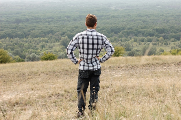 Joven mirando hacia abajo en el bosque de tiro completo