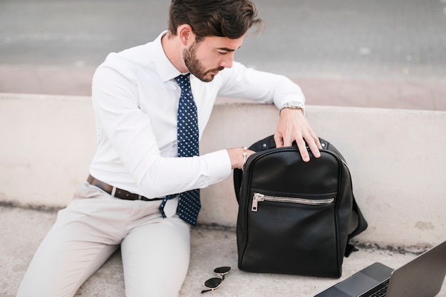 Foto gratuita joven mirando dentro de la mochila negra