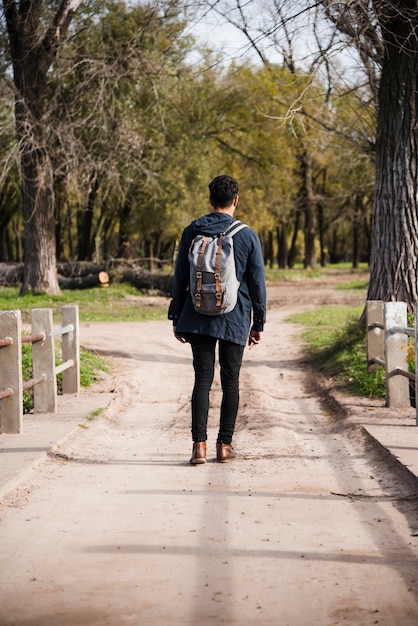 joven con mochila caminando en el parque