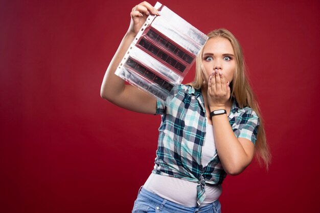 La joven modelo rubia revisa las escenas de la película polaroid y se ve sorprendida y decepcionada.