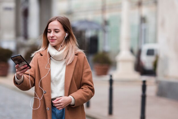 Joven moderna escuchando música en auriculares con espacio de copia