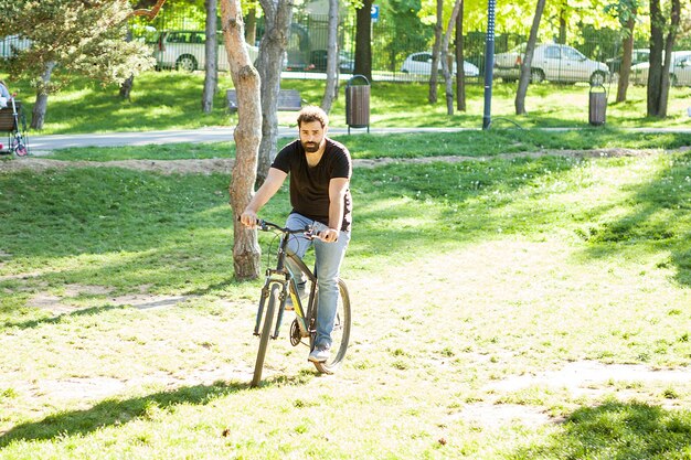 Joven montando una bicicleta en el parque en verano