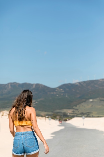 Foto gratuita joven morena contra montañas en la luz del sol