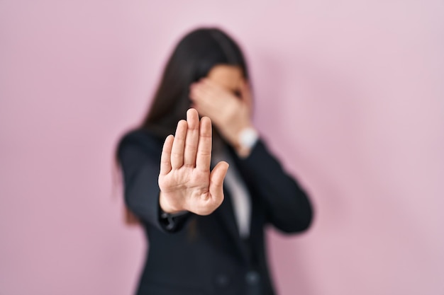 Foto gratuita joven morena con estilo de negocios sobre fondo rosa cubriendo los ojos con las manos y haciendo un gesto de alto con expresión de tristeza y miedo concepto avergonzado y negativo