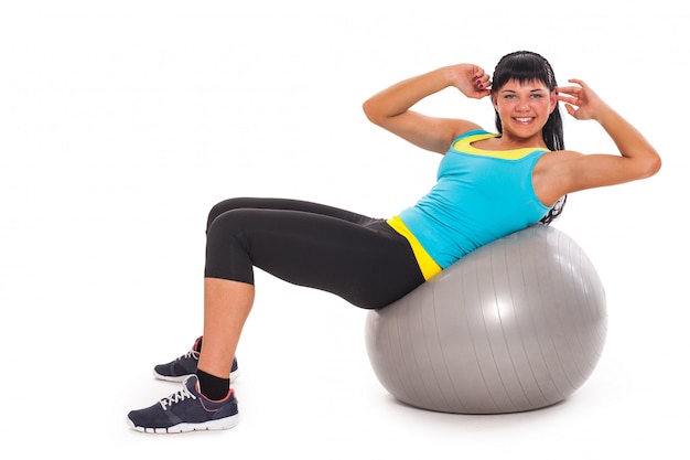 Joven morena feliz haciendo ejercicio con fitball