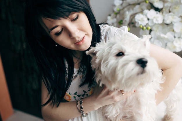 Joven morena con perro encantador en casa