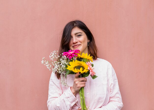 Foto gratuita joven morena con ramo de flores florecientes