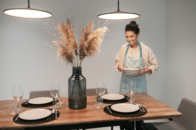 Joven morena sirviendo la mesa en la cocina