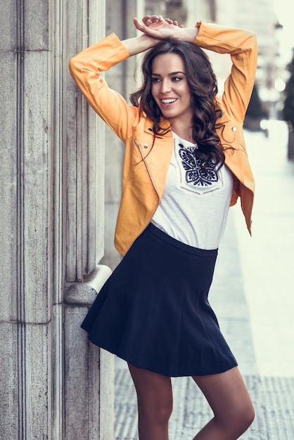 Joven morena sonriente en fondo urbano.