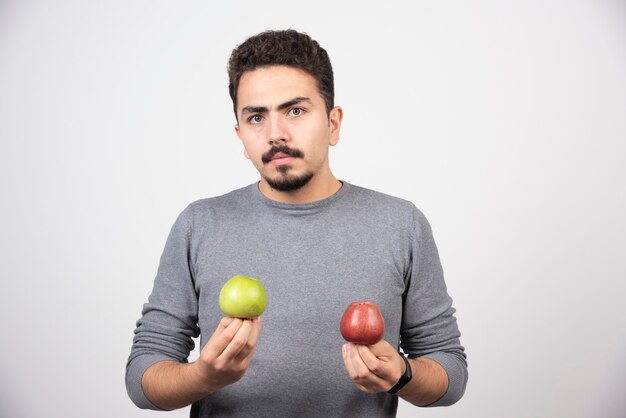 Joven morena sosteniendo dos manzanas en gris.