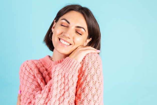 Foto gratuita joven morena en suéter rosa aislado en la pared azul