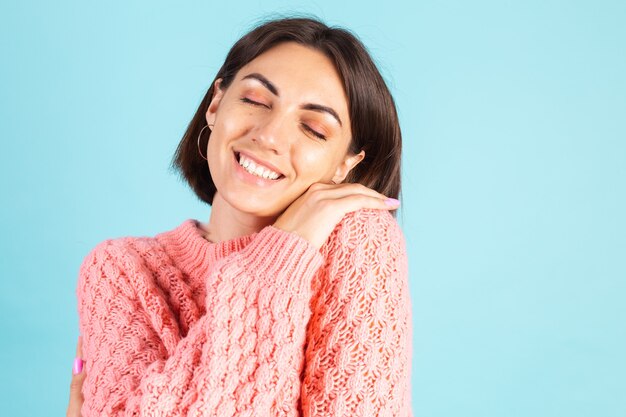 Joven morena en suéter rosa aislado en la pared azul