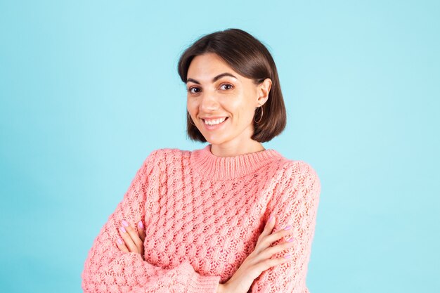 Joven morena en suéter rosa aislado en la pared azul