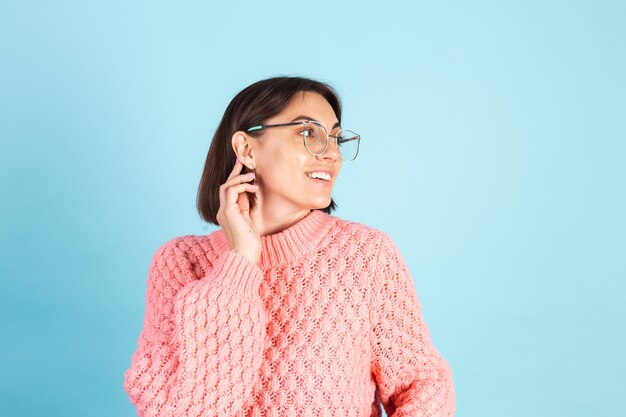 Joven morena en suéter rosa aislado en la pared azul