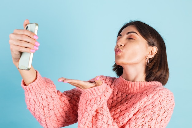 Joven morena en suéter rosa aislado en la pared azul