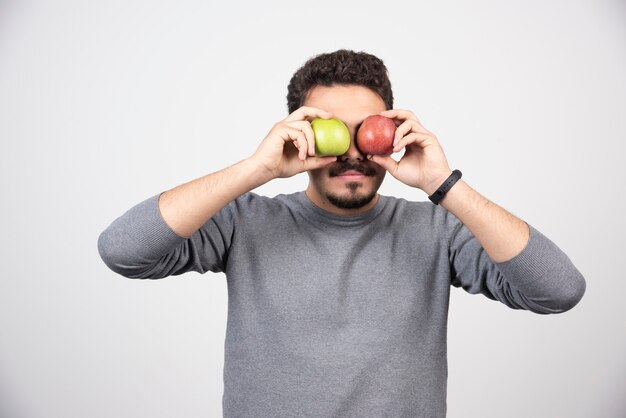 Joven morena tapándose los ojos con manzanas.