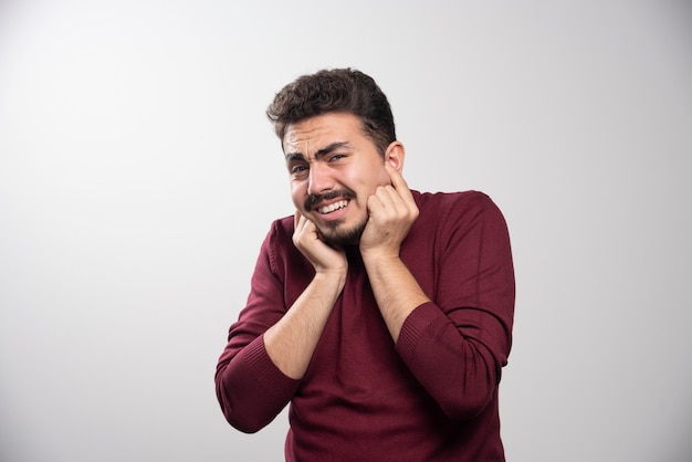 Un joven moreno tapándose los oídos y posando.