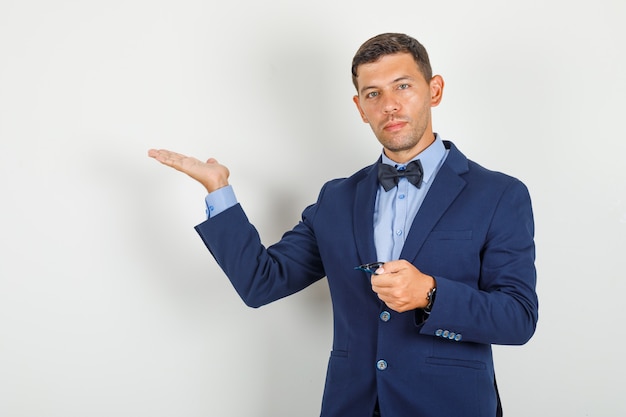 Foto gratuita joven mostrando algo con gafas en traje