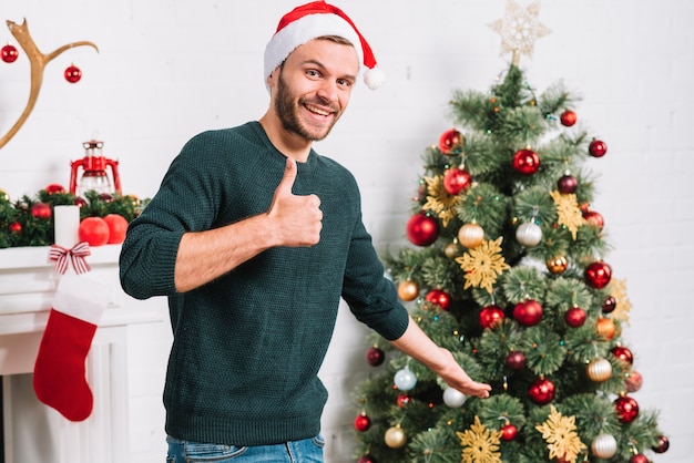 Joven mostrando buen árbol de Navidad cercano