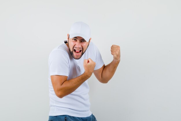 Joven mostrando gesto de ganador en camiseta y mirando feliz, vista frontal.