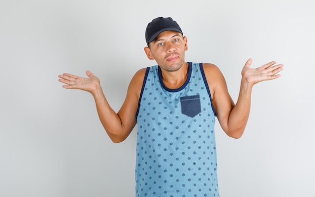 Joven mostrando gesto de impotencia en camiseta azul con gorra