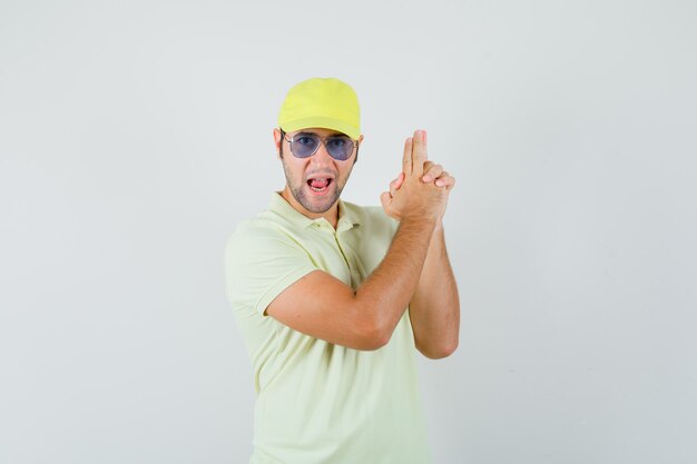 Joven mostrando gesto de pistola en uniforme amarillo y mirando confiado.