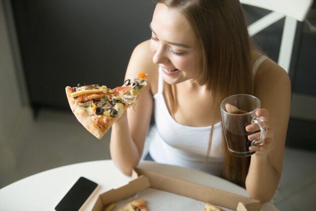 Joven muchacha sonriente con una rebanada de pizza