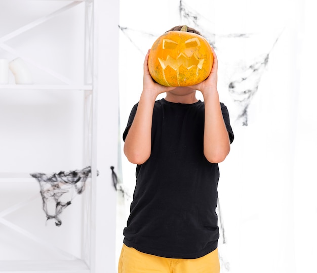 Foto gratuita joven muchacho con calabaza tallada de halloween