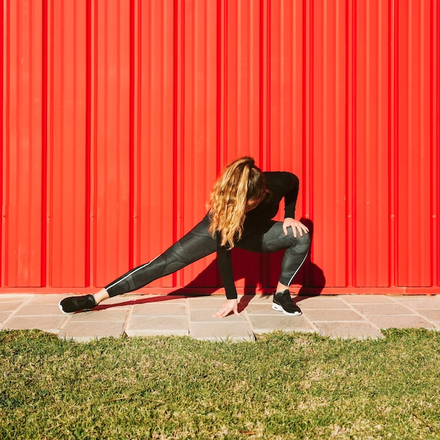 Foto gratuita joven mujer abalanzándose cerca de la pared roja
