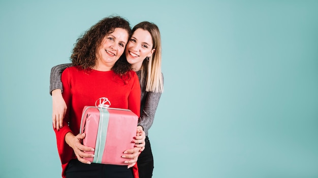 Joven mujer abrazando a madre con regalo