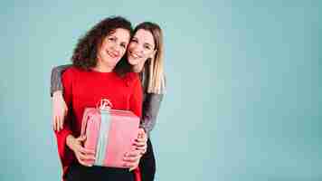 Foto gratuita joven mujer abrazando a madre con regalo