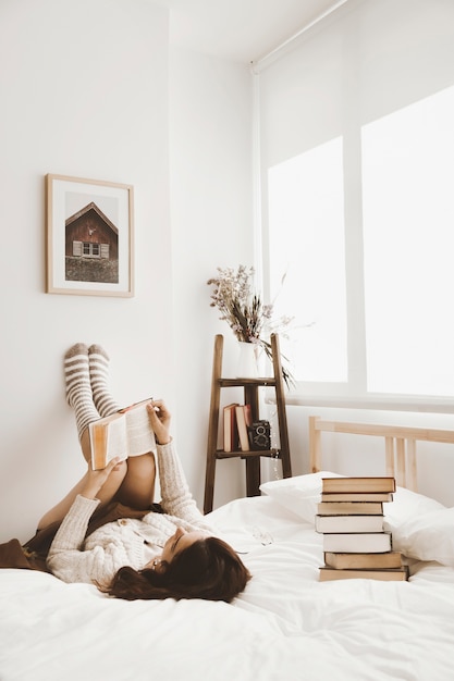 Joven mujer acostada en la cama con el libro