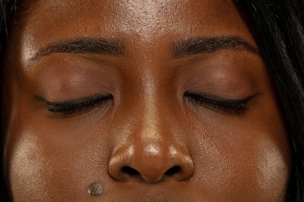 Foto gratuita joven mujer afroamericana aislada sobre fondo amarillo estudio, expresión facial. ojos de mujer hermosa cerca retrato. concepto de emociones humanas, expresión facial.