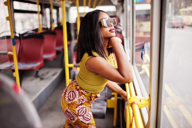 Joven mujer afroamericana con estilo en gafas de sol modernas en un autobús