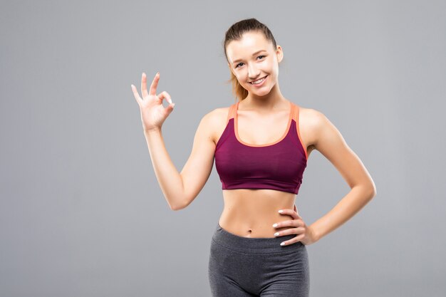 Joven mujer alegre sonriente feliz en ropa deportiva mostrando gesto OK, aislado