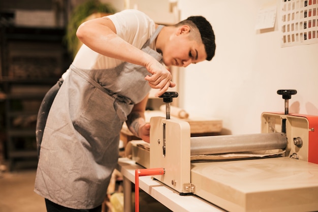 Joven mujer alfarera ajustando la máquina en su taller.