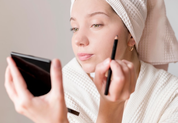 Joven mujer aplicando delineador de ojos