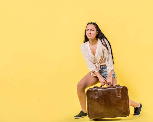 Foto gratuita joven mujer arrastrando maleta vintage