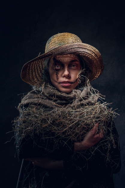 Joven mujer artística está posando para el fotógrafo en un papel de espeluznante espantapájaros.