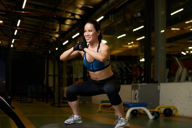 Joven mujer asiática en buena forma física haciendo sentadillas en un gimnasio