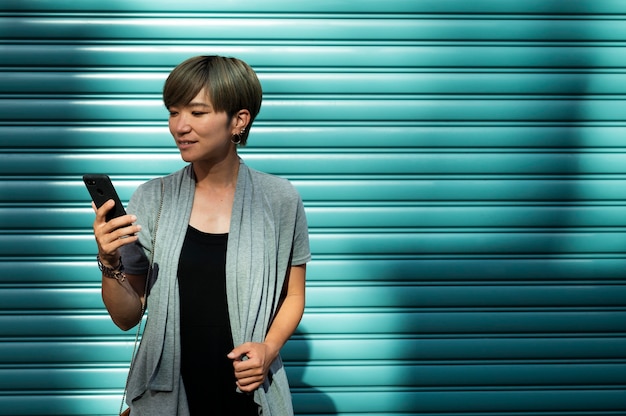 Joven mujer asiática comprobando su teléfono al aire libre