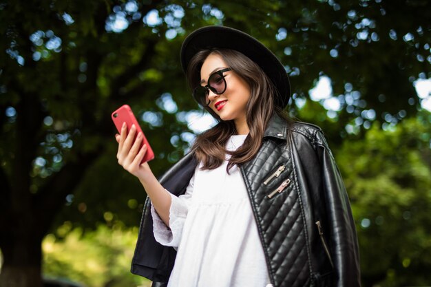 Joven mujer asiática enviando mensajes de texto celular en la calle de la ciudad