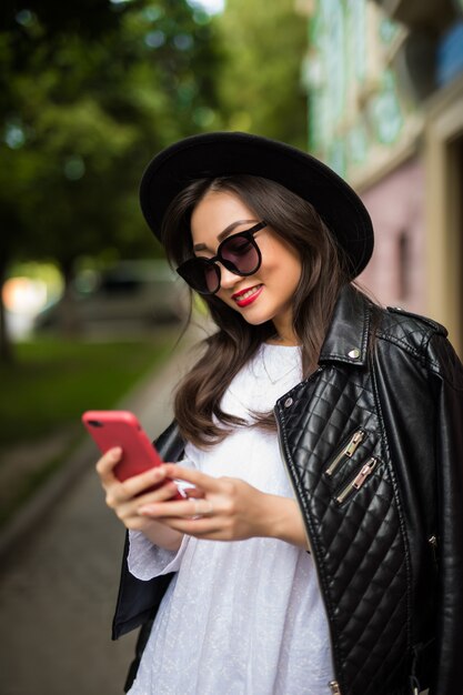 Joven mujer asiática enviando mensajes de texto celular en la calle de la ciudad