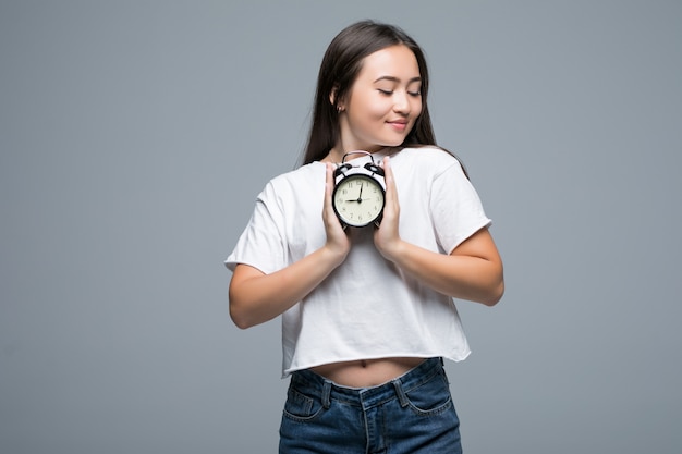 Joven mujer asiática sonrisa con un reloj aislado sobre fondo gris