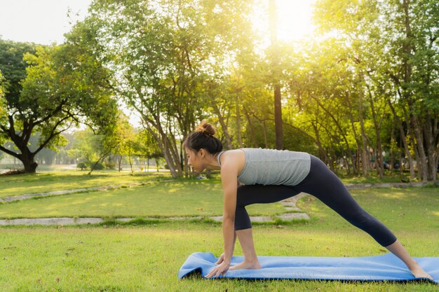 Joven mujer asiática de yoga al aire libre mantiene la calma y medita mientras practica yoga