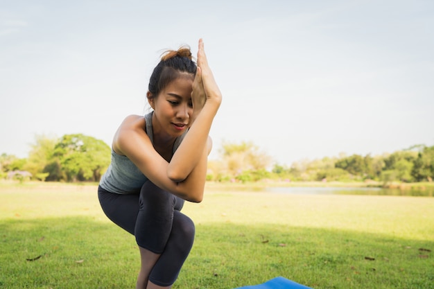 Joven mujer asiática de yoga al aire libre mantiene la calma y medita mientras practica yoga