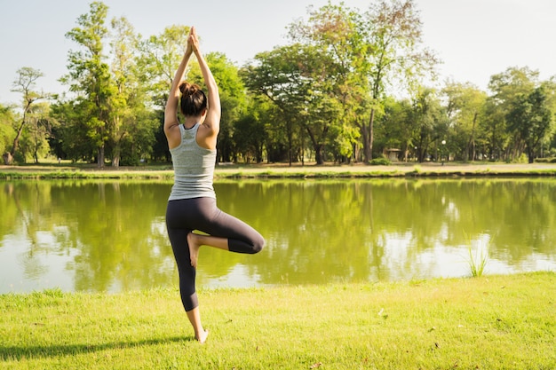 Joven mujer asiática de yoga al aire libre mantiene la calma y medita mientras practica yoga